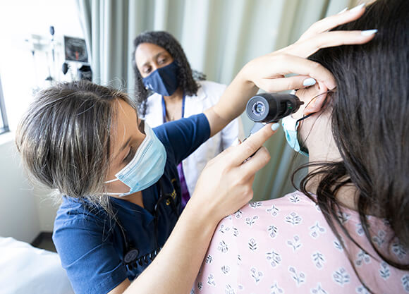 Nursing students examine a patient.