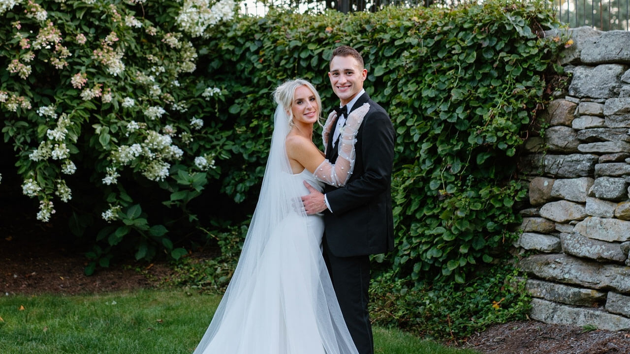 Gabrielle in her wedding dress standing with husband, Joey.