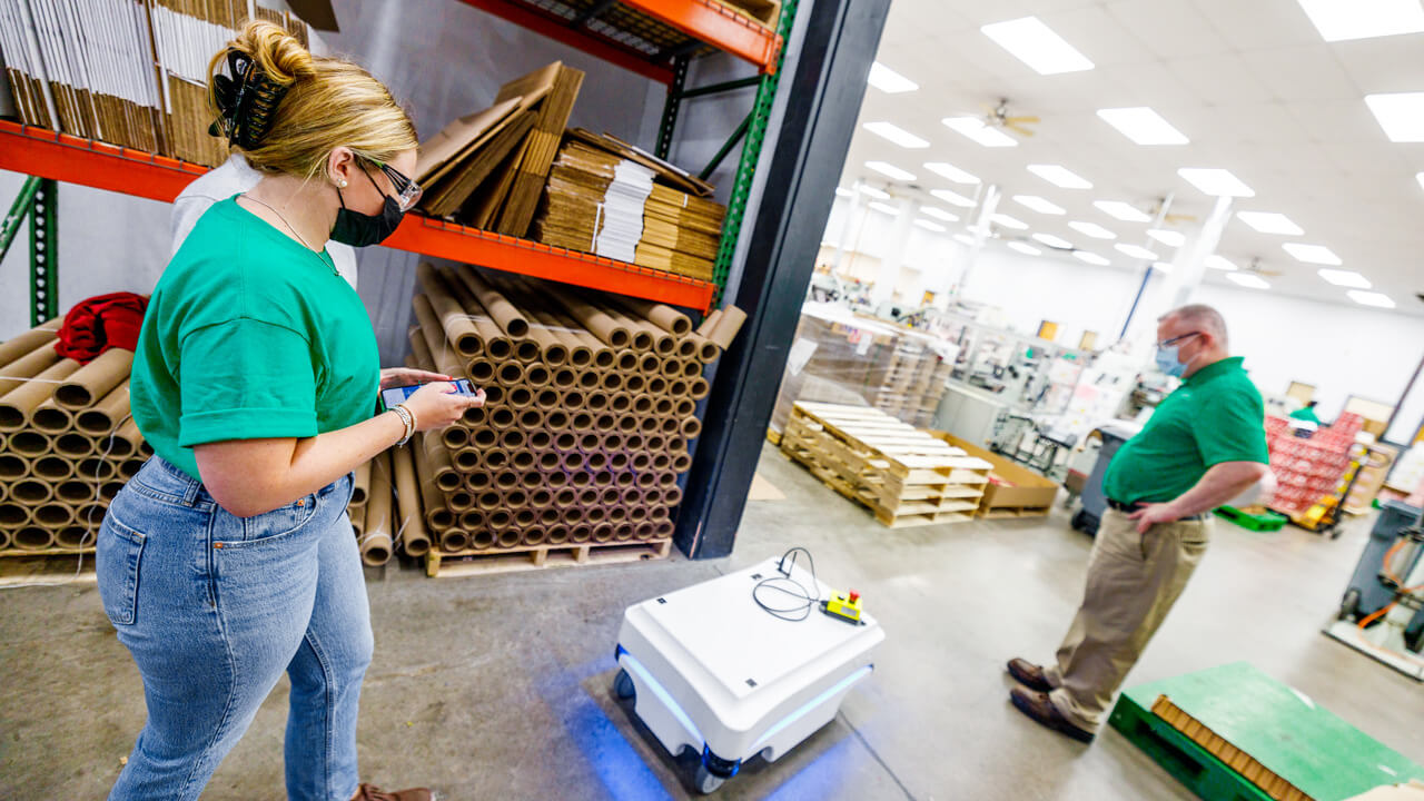 Student testing a robot in a warehouse.