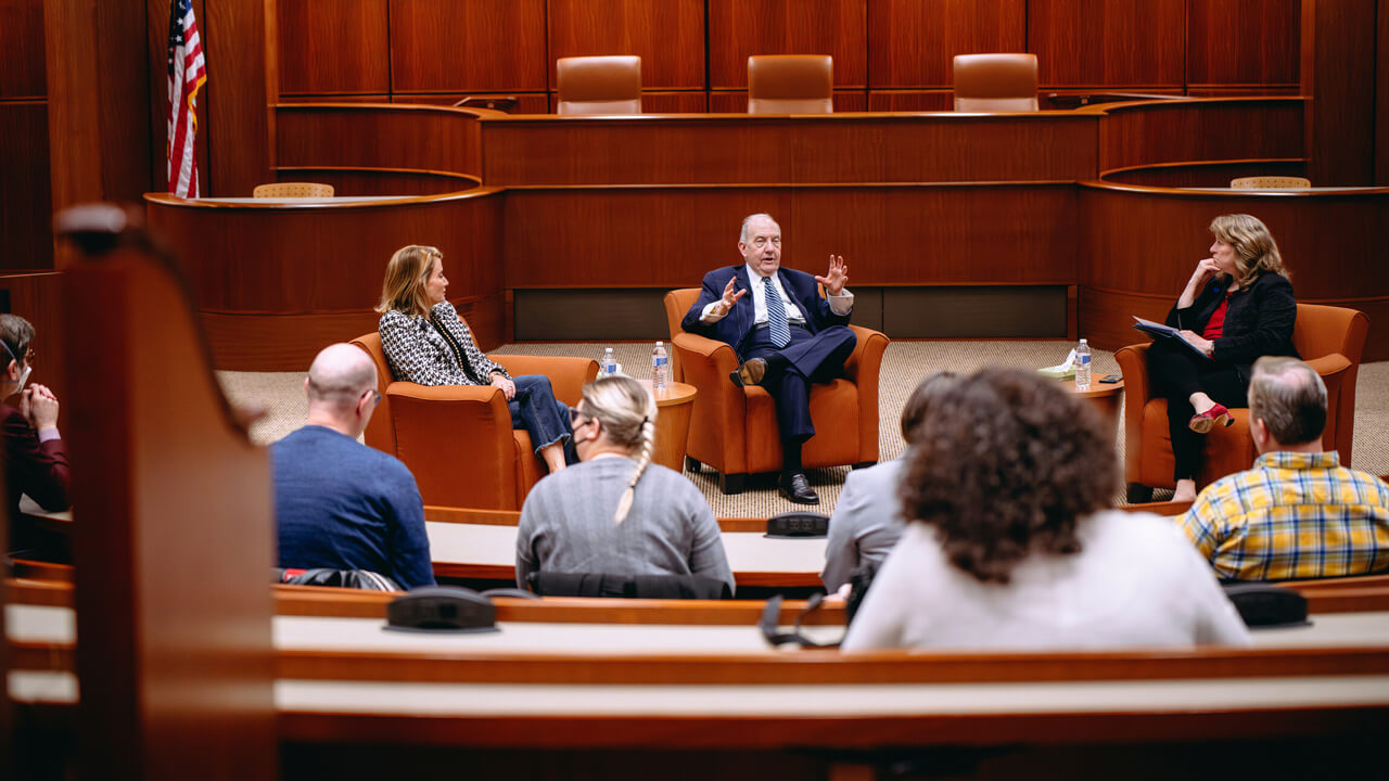 Individuals sit and discuss topic in law courtroom