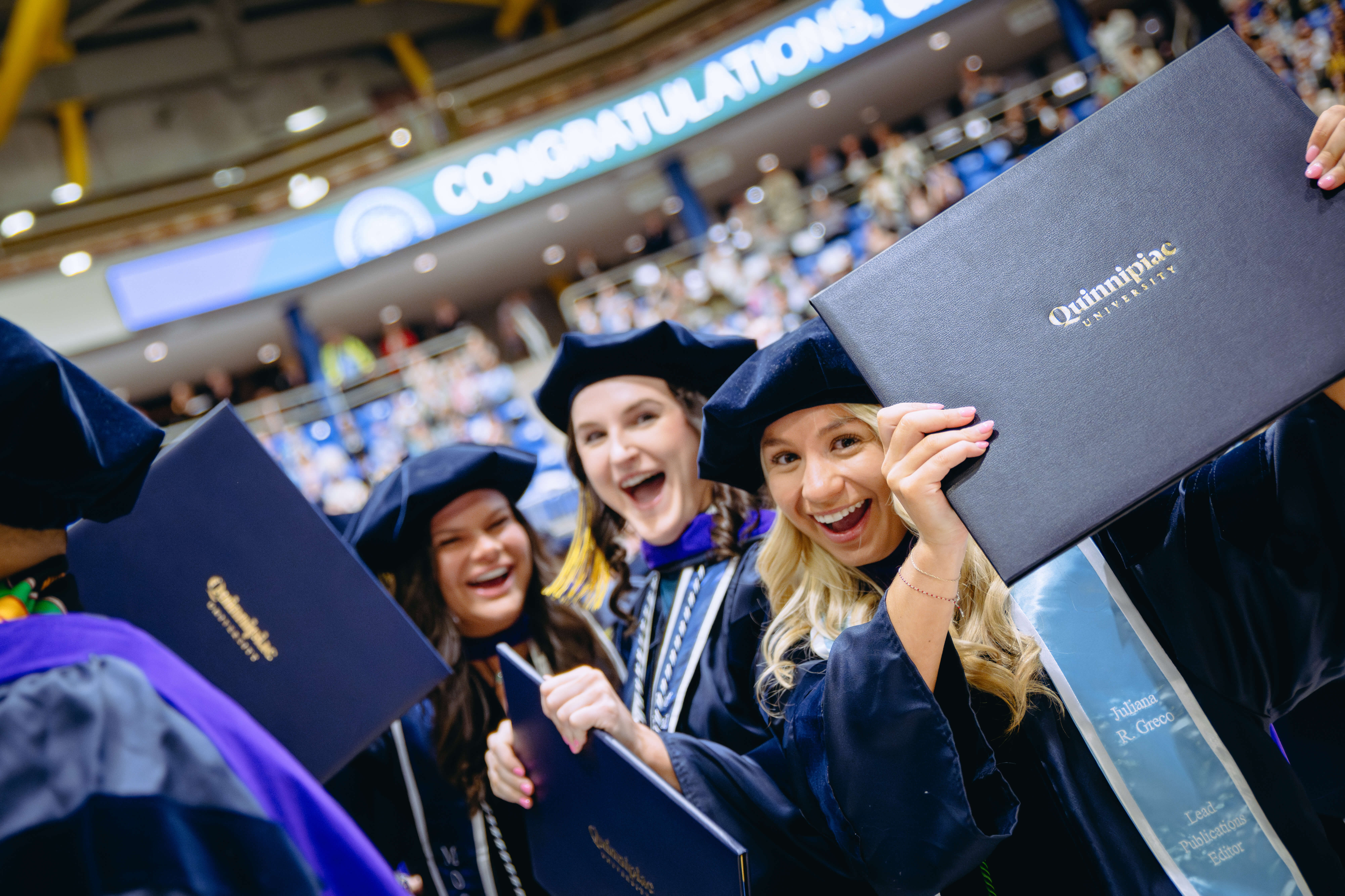 A School of Law graduate holds her degree over her head.