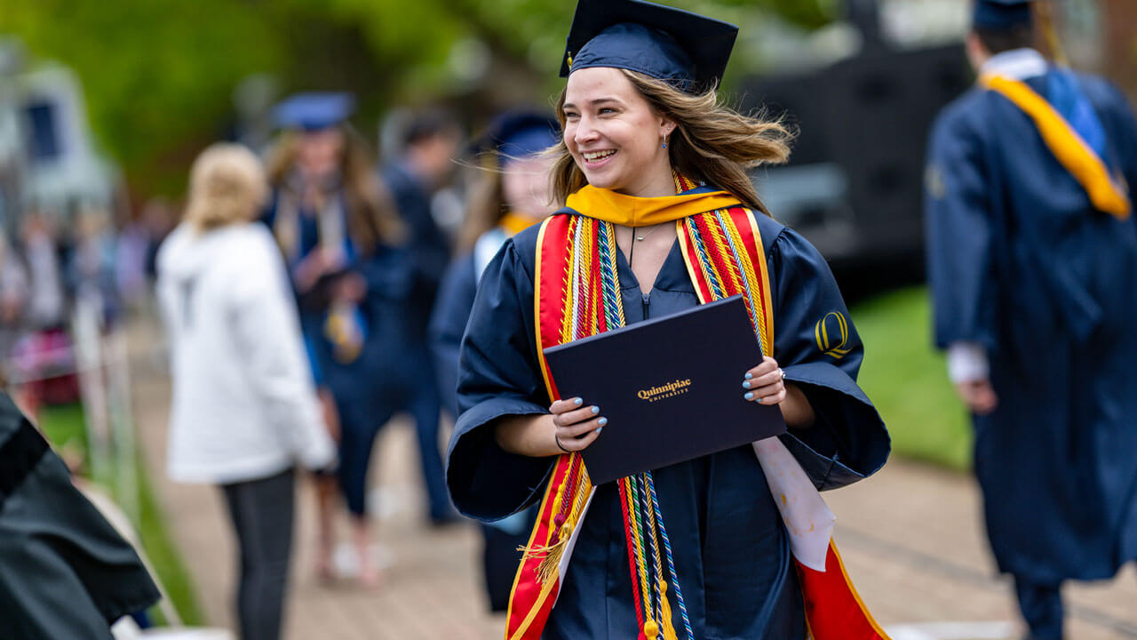 SOC graduate holding their degree smiling and walking