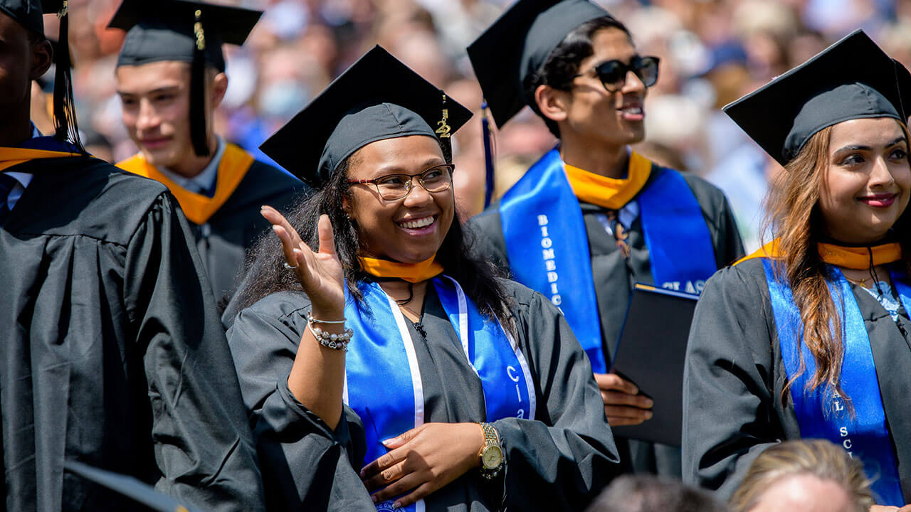 Graduates smile and look up at the stage