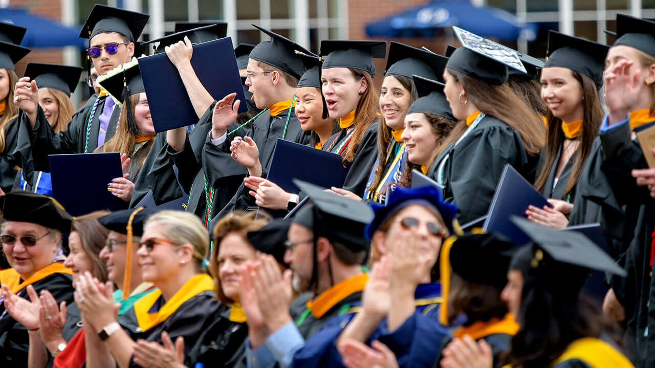 Dozens of graduates cheer from their seats