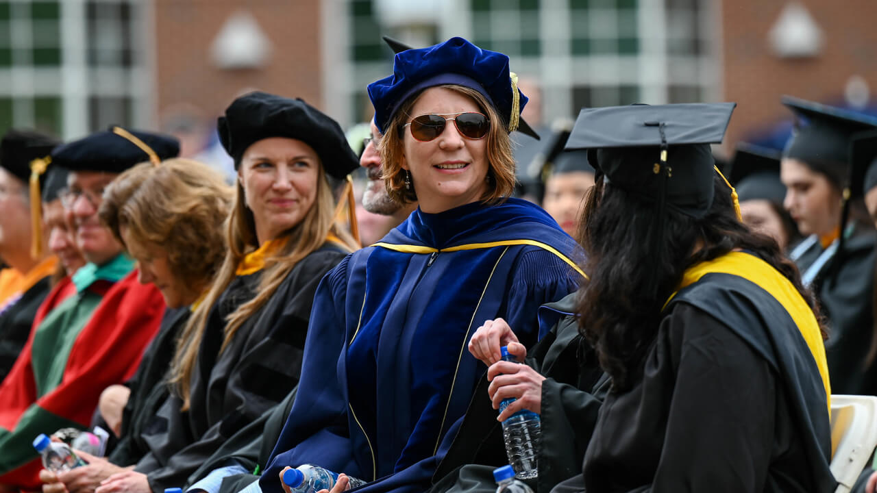 Faculty members smile while they are sitting