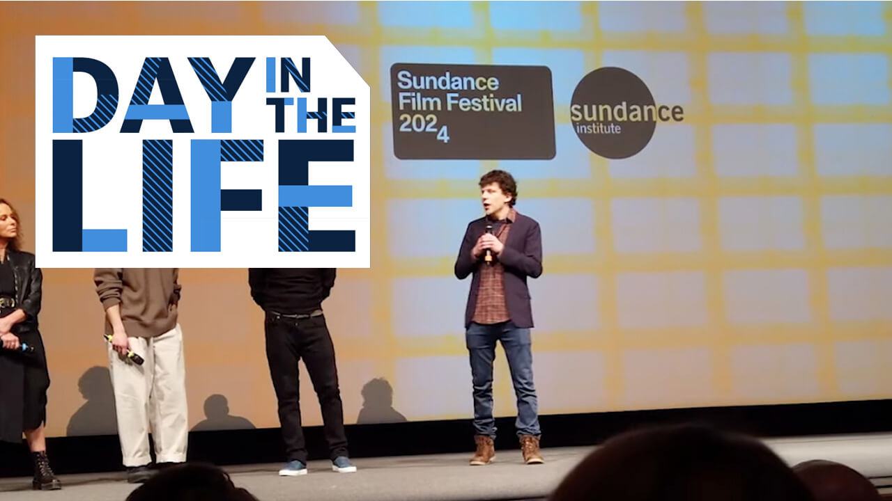 A man on stand with "Sundance Film Festival 2024" projected behind him, plays video