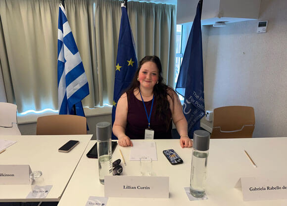 Quinnipiac student Lillian Curtin sitting at a table with her name tag displayed