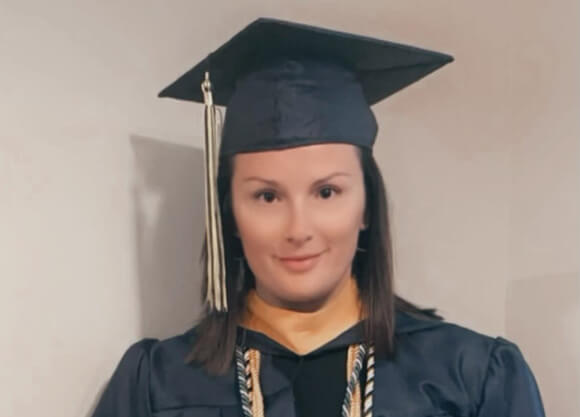 Jamilynn Miller smiles while wearing commencement cap and gown