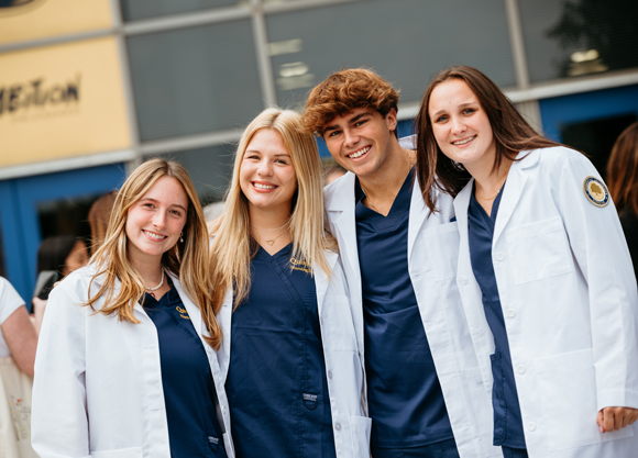 Students stand in their white coats