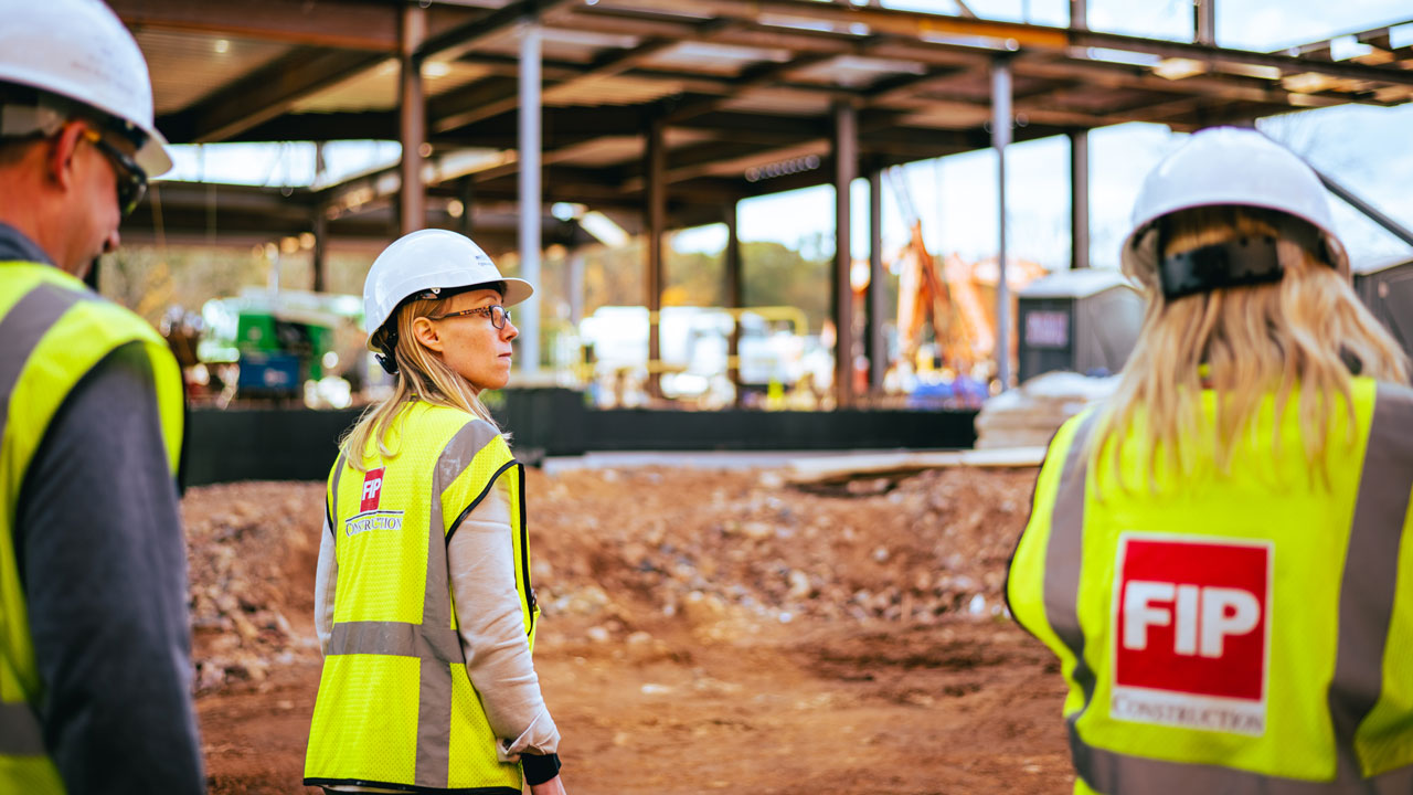 Construction workers stand around and talk on site.