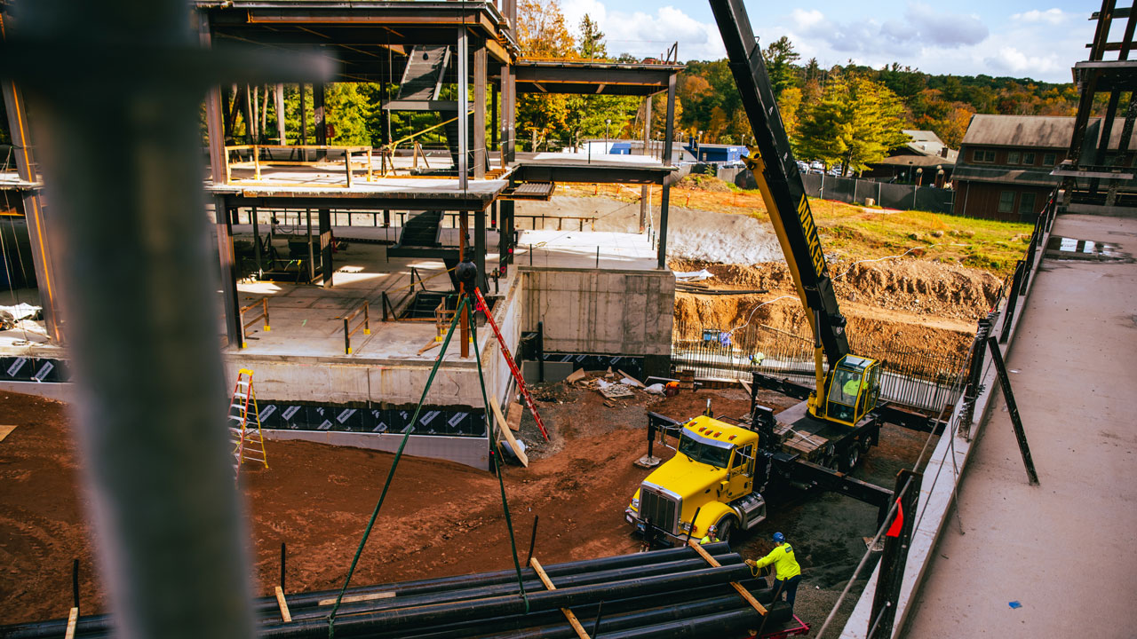 A pole partly blocks the view of the south quad construction site and a large crane.