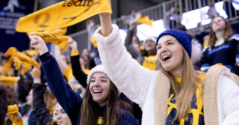 Students cheer and swing rally towels during a hockey game