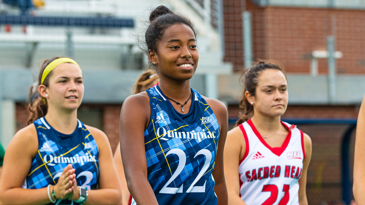 Kaylah Igarta smiles as she walks across the field hockey field in her jersey.