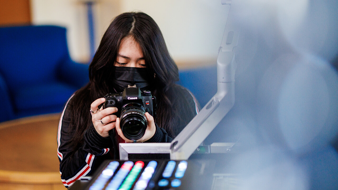 A high school student takes a photo of a sound board.